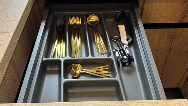 Un cajón de cocina con utensilios y una cafetera.