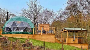 A geodesic dome structure with a wooden deck and outdoor seating area. - Ashdown Luxury Dome (Hoath)