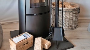 A wood-burning stove, a basket of bread, and a box of magazines on a wooden floor. - Ashdown Luxury Dome (Hoath)