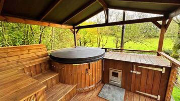 Een hottubgedeelte met houten banken en een overdekt dak, omgeven door een houten terras.
