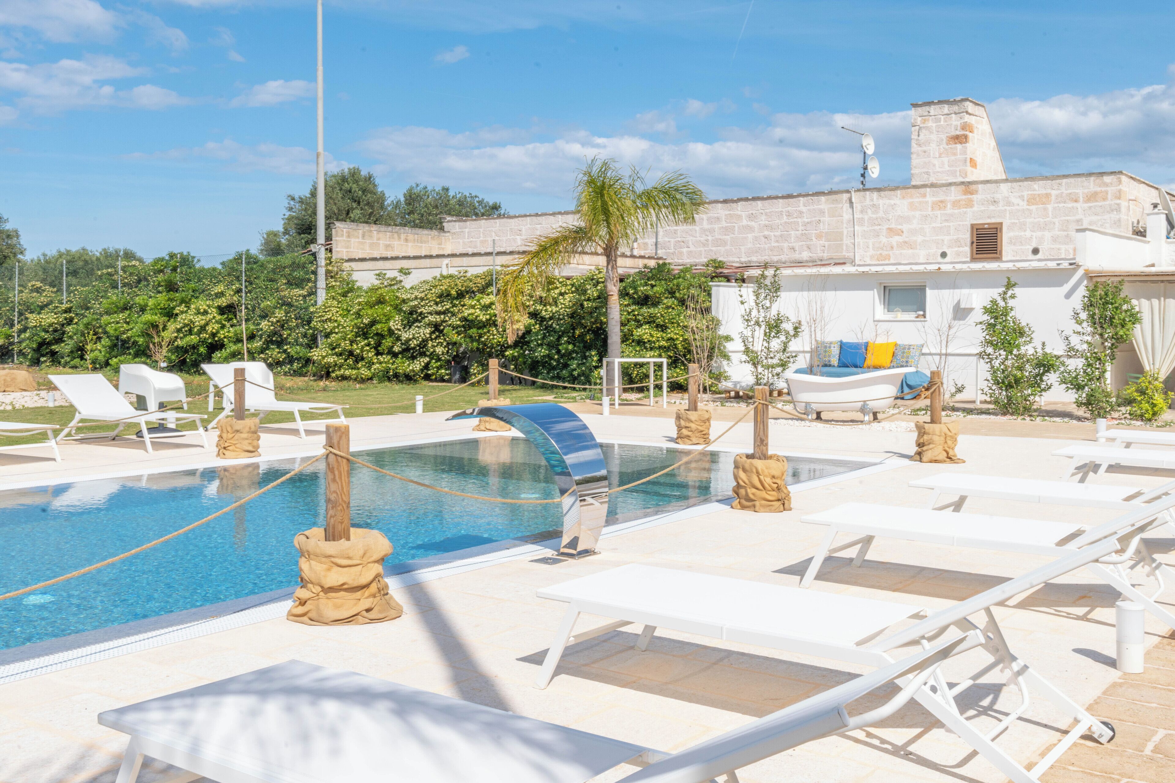 Uma área de piscina com espreguiçadeiras e piscina transparente.