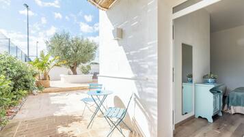 Un patio con suelo de piedra, una mesa pequeña y sillas azules.