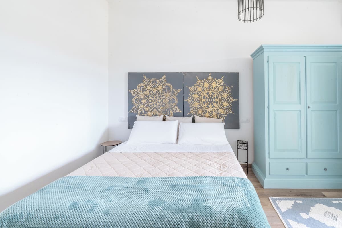 Un dormitorio con una cama, dos paneles decorativos en la pared, un armario y una mesita de noche.