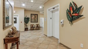 Un couloir avec un banc en bois, un miroir, un tableau encadré et une plante en pot.