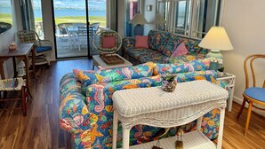 A cozy living room with a colorful sofa, wicker furniture, and a view of the outdoors. - WATERFRONT!!!  Literally on the water of beautiful Bogue Sound. No better view. (Atlantic Beach)