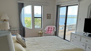 A bedroom with a large bed, a chair, a TV, and a view of the water. - WATERFRONT!!!  Literally on the water of beautiful Bogue Sound. No better view. (Atlantic Beach)