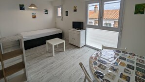 Pieni, hyvin valaistu huone, jossa on sänky, työpöytä, televisio ja ikkuna, josta on näkymä rakennuksiin.