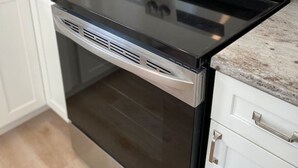 Une cuisine moderne équipée d’un four en acier inoxydable, d’un grille-pain encastré et d’une machine à café posée sur le plan de travail.