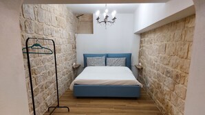Un dormitorio con cama, perchero, candelabro y suelo de madera.