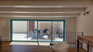Habitación amplia con un gran ventanal corredero que da a un espacio exterior con mesa y sillas.