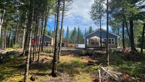 Eine Hütte im Wald mit einer Terrasse und einem großen Fenster mit Blick auf den Wald.