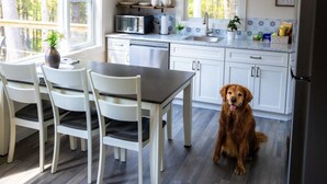 Eine moderne Küche mit weißen Schränken, einem Edelstahlkühlschrank und einem Essbereich mit Tisch und Stühlen.