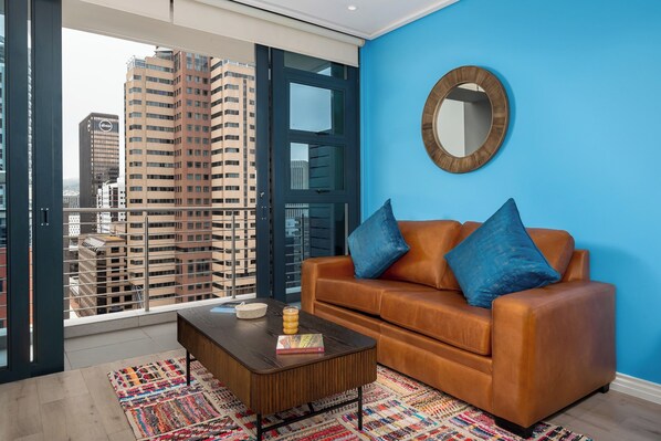 A modern living room with a blue wall, a brown leather sofa, and a coffee table.