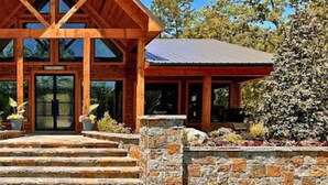 Una casa rústica amb una estructura de fusta destacada i unes escales de pedra que condueixen a l'entrada.