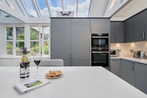 Una cucina moderna con mobili grigi, forno integrato e un'ampia finestra con vista sul verde.