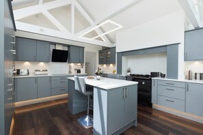 A modern kitchen with grey cabinetry, a central island with bar stools, and built-in appliances.