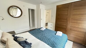 A bedroom with a bed, a wardrobe, a mirror, and a door leading to a bathroom. - Captivating 1-bed Apartment in London (London)