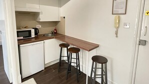 A compact kitchen with a microwave, sink, and bar stools. - Captivating 1-bed Apartment in London (London)