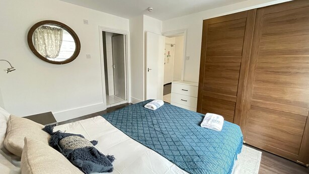 A bedroom with a bed, a wardrobe, a mirror, and a door leading to a bathroom. - Captivating 1-bed Apartment in London (London)