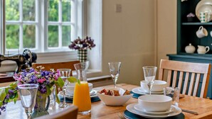 A dining table set with plates, bowls, glasses, and a vase of flowers. - 3 Bed in Tavistock (oc-t29334) (Gulworthy)