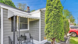 A small house with a porch, a table with chairs, and a tall tree. - Quaint 1 Bedroom House on N Martin Luther King Jr Blvd, Lansing: Your Ideal Home (Lansing)
