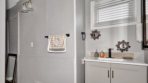 A bathroom with a white sink, a towel with a family friends message, and decorative wall mirrors. - Quaint 1 Bedroom House on N Martin Luther King Jr Blvd, Lansing: Your Ideal Home (Lansing)