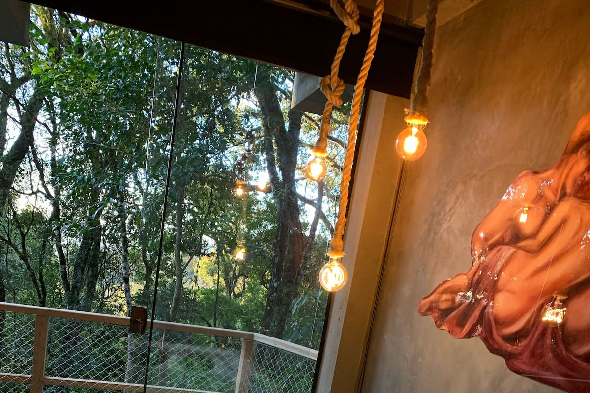 A hot tub with a view of trees through a window, a rope light, and a statue.