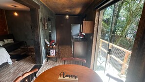 Una habitación acogedora con una mesa de comedor de madera, una lámpara colgante y vistas al exterior a través de amplios ventanales.