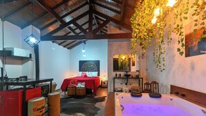 Una habitación acogedora con una bañera grande, una cama con ropa de cama roja y un techo de madera rústica.
