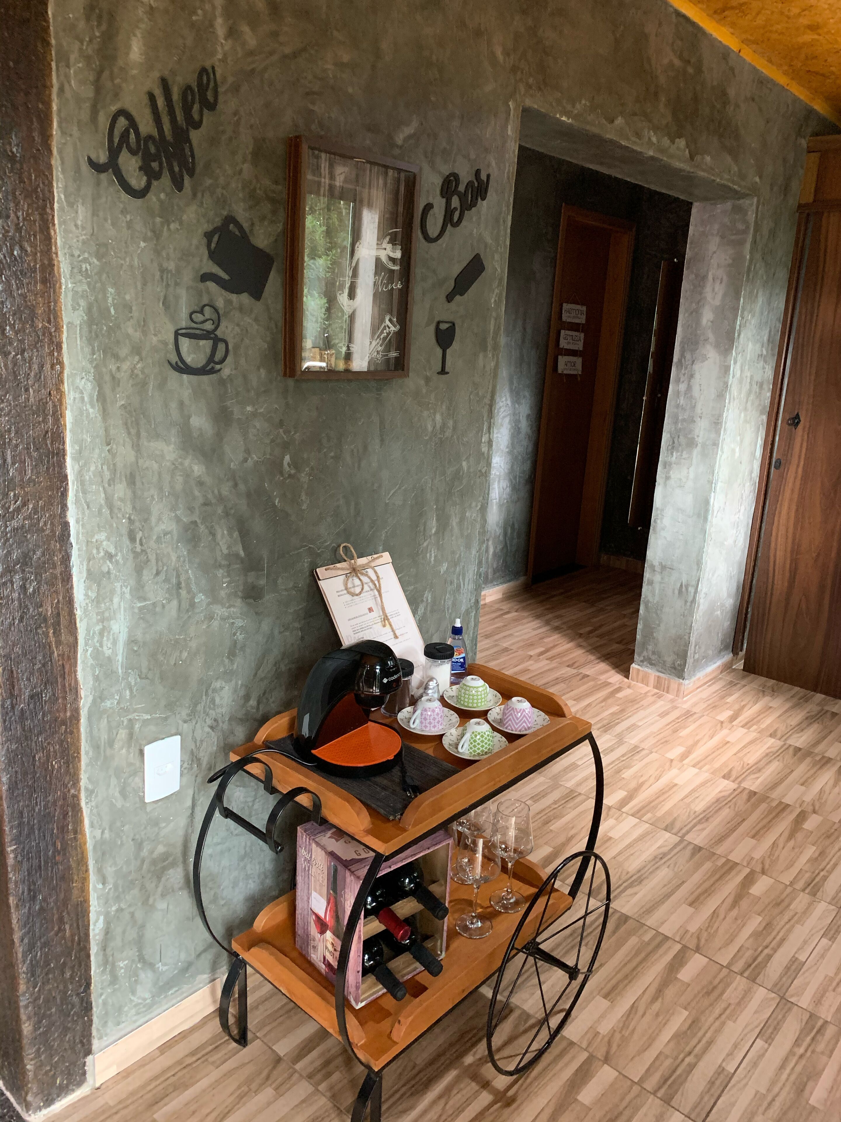 A room with a coffee cart, a framed picture, and a wall with 'Coffee Bar' text.