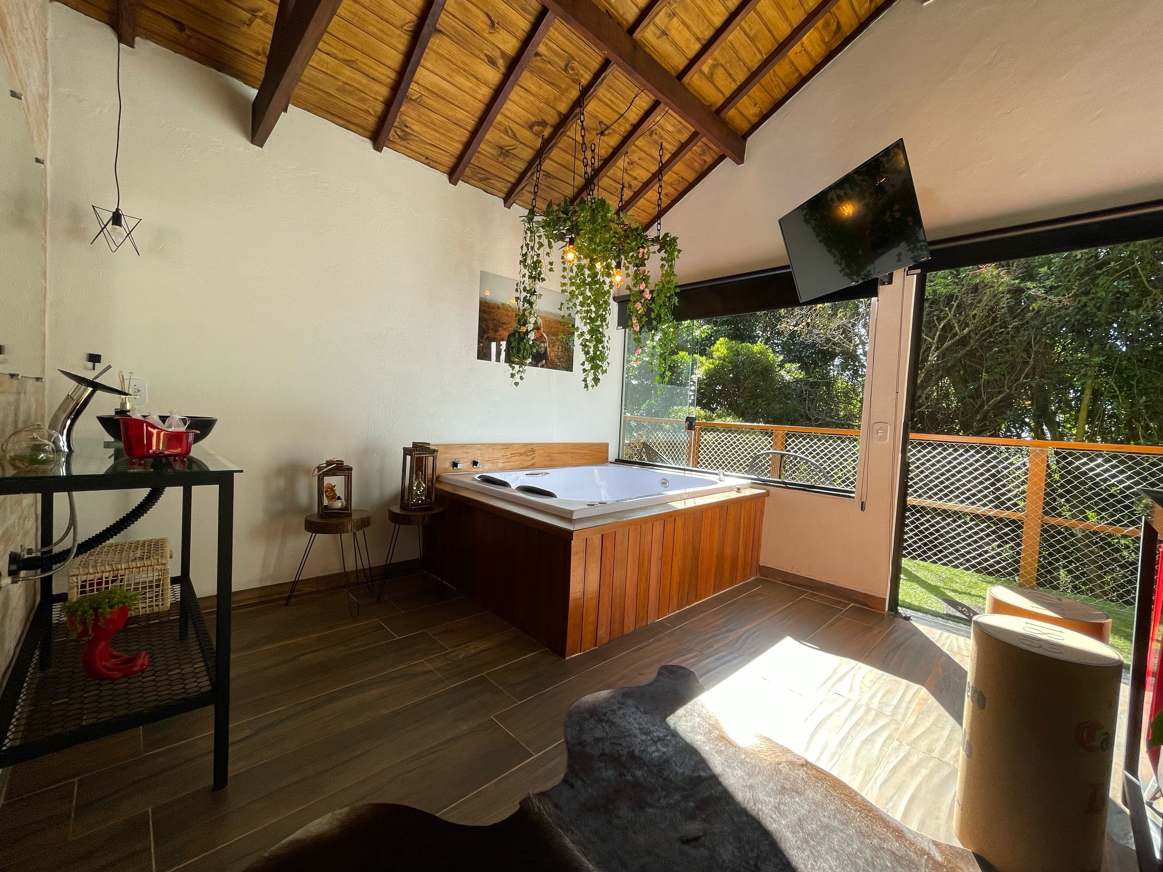 Une chambre moderne avec un plafond en bois, une grande fenêtre, un lit, une petite table et un téléviseur fixé au mur.