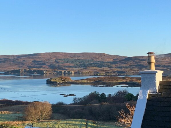 A view of a lake with surrounding hills and a chimney in the foreground. - Cosy Sea View Skye Cottage for 6 (Glendale)