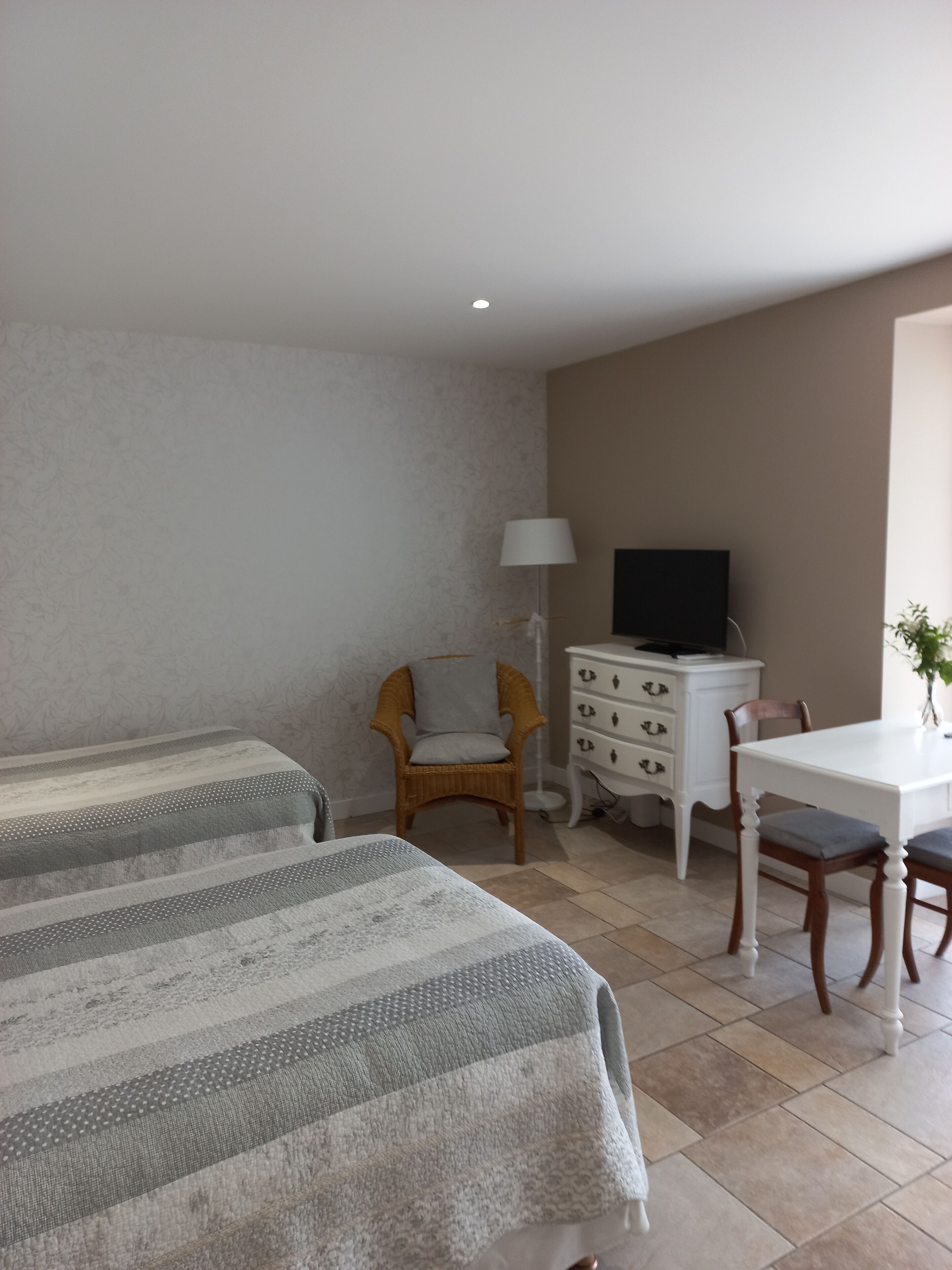 Ein Hotelzimmer mit zwei Betten, einem Schreibtisch, einem Sessel, einem Schminktisch und einem Fernseher.