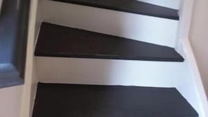 Una escalera curva con peldaños oscuros y paredes blancas.