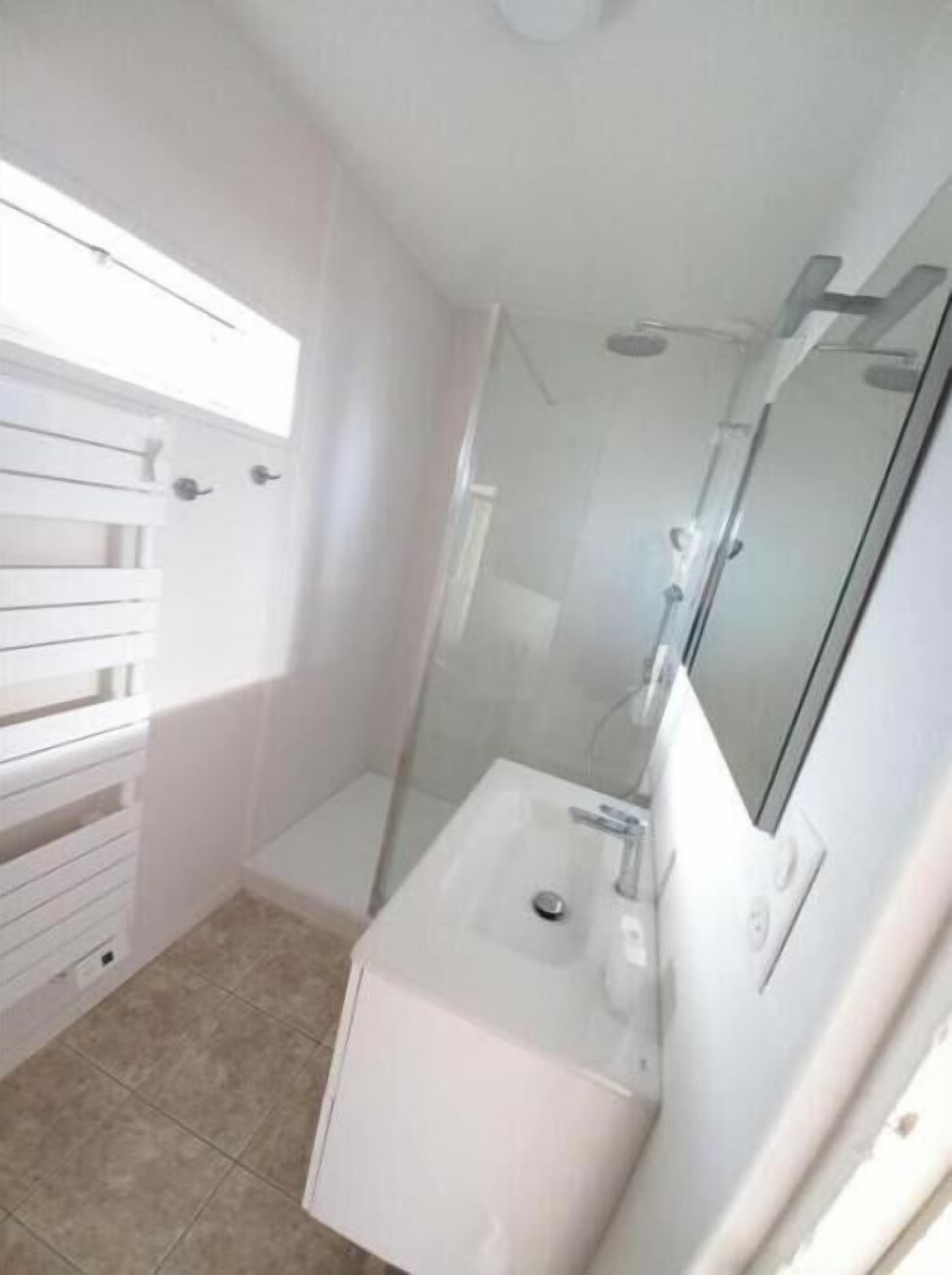 A bathroom with a white sink, a mirror, and a shower enclosure.