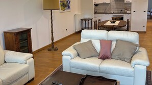 A living room with a white sofa, a coffee table, and a dining area with a table and chairs. - 3 bedroom apartment in venice (Venezia)