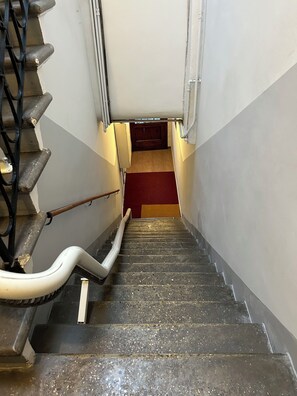 Un escalier avec une rampe, une moquette rouge et une porte en haut.