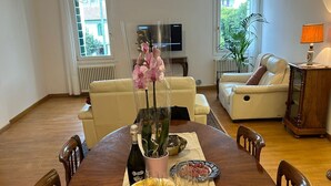 A dining area with a wooden table set for a meal, surrounded by chairs. There is a potted orchid on the table, a bottle of wine, and a bowl of chips. - 3 bedroom apartment in venice (Venezia)