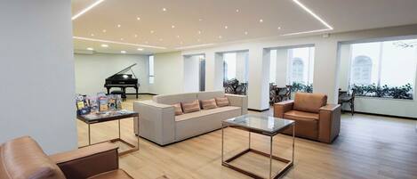 Uma sala de estar ampla com um piano, um sofá e poltronas de couro.