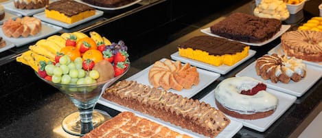 A buffet with various desserts and fruits.
