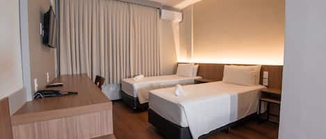 Habitación de hotel con dos camas, un escritorio y una televisión.