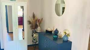 Un interior moderno con suelo de madera, un armario azul, un espejo y un pequeño banco.