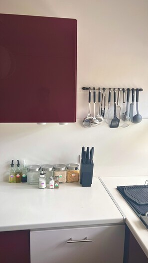 A kitchen with a white countertop, a red cabinet, and various kitchen utensils and containers. - Blue Seahorse Flat - T3 Avignon Intra-muros - GARAGE WIFI CLIM (Avignon)
