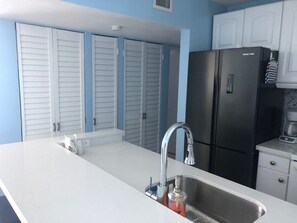 A kitchen with a stainless steel sink, a black refrigerator, and white cabinets. - 2Bed 2Bath Marbella 15th Floor Condo with STUNNING Beachfront Views, WasherDryer (Carolina)