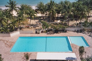 A rectangular pool with a clear blue water surface, surrounded by a sandy beach and palm trees. - 2Bed 2Bath Marbella 15th Floor Condo with STUNNING Beachfront Views, WasherDryer (Carolina)