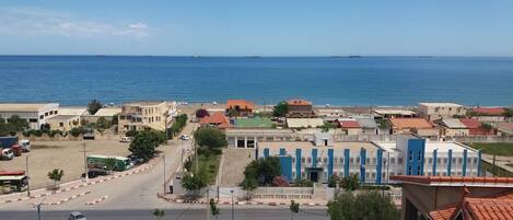 Un pueblo costero con edificios, una carretera y el mar al fondo.