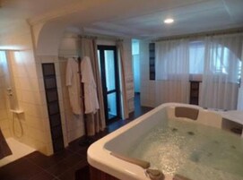 Un baño con bañera, ducha e inodoro. Hay un perchero y una cortina.