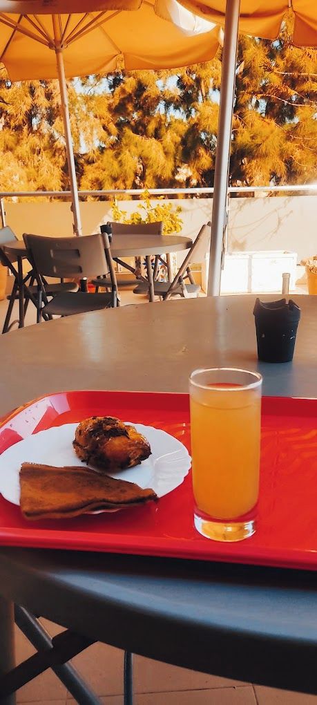 A table with a meal and a drink, outdoor seating, and trees in the background.