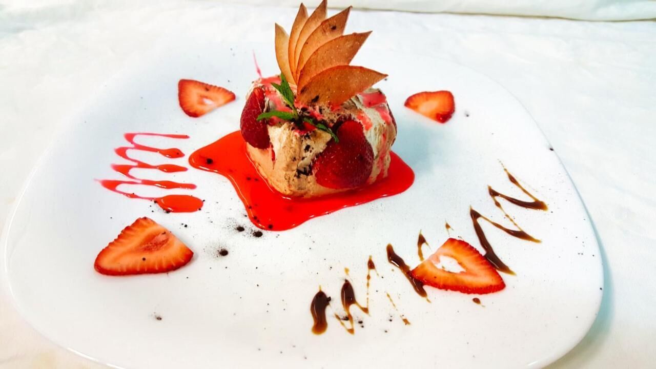 Dessert auf einem weißen Teller mit Erdbeeren und Schokoladensauce.