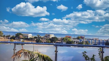 Un pueblo costero con edificios a lo largo del paseo marítimo, cielo despejado y mar tranquilo.